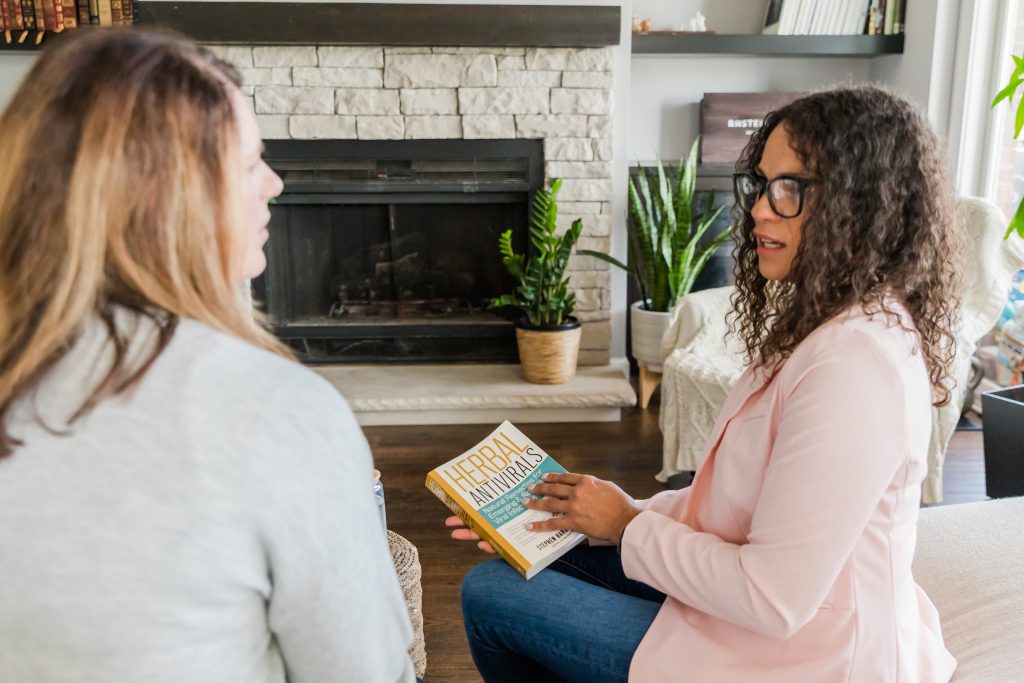 Doris is showing a wellness coaching client a book about herbal remedies. 