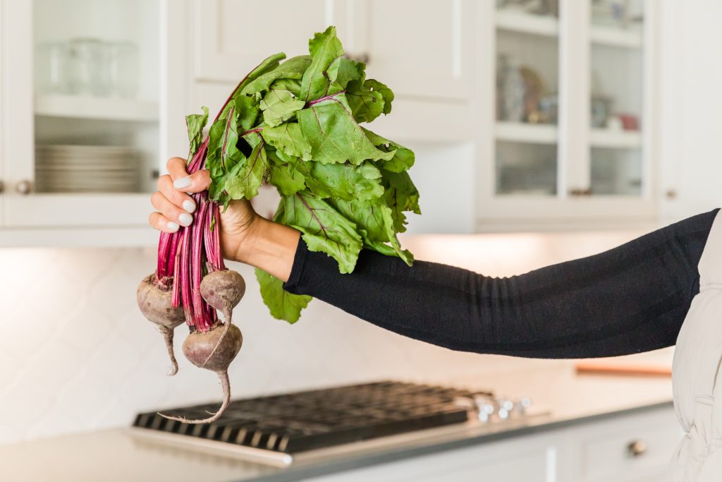 Doris is holding a bunch of red beets.