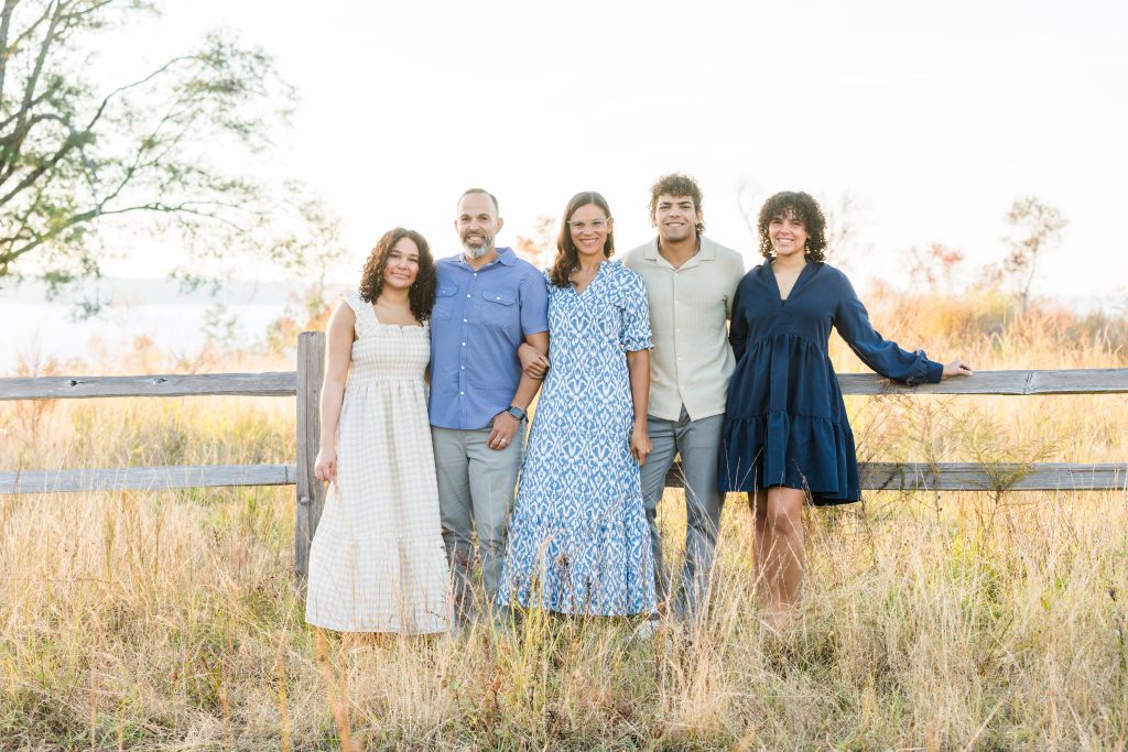 in this image you see Doris family on a field standing by a fence 